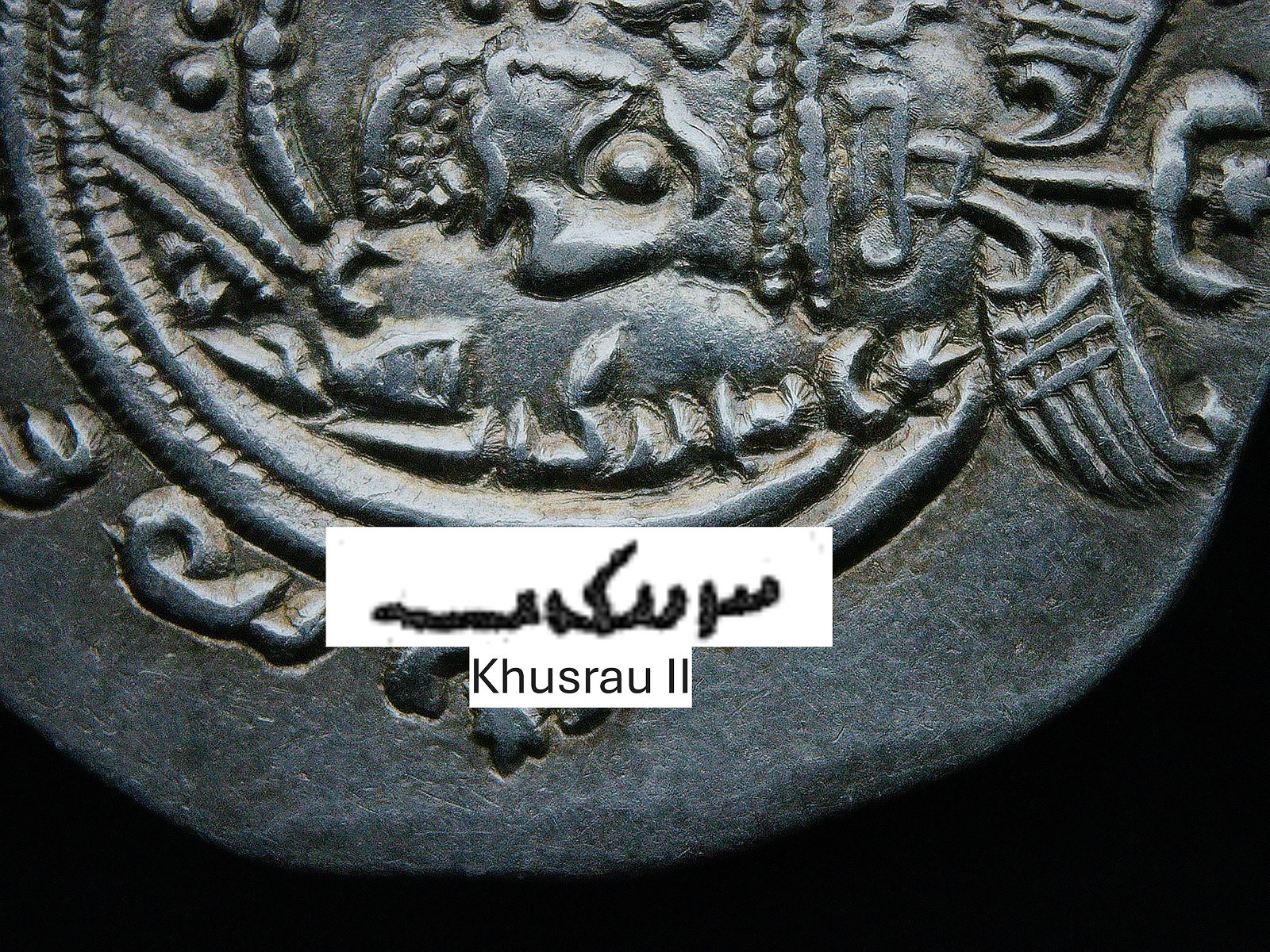 Pahlavi Inscription – Name of Khusrau II on Sasanian Coin Close-up of Pahlavi script on a Sasanian silver drachm showing the name of Khusrau II in Middle Persian.
